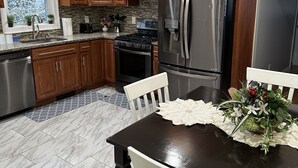 A modern kitchen with wooden cabinets, stainless steel appliances, and a dining table with chairs. - Charming quiet (Manchester)