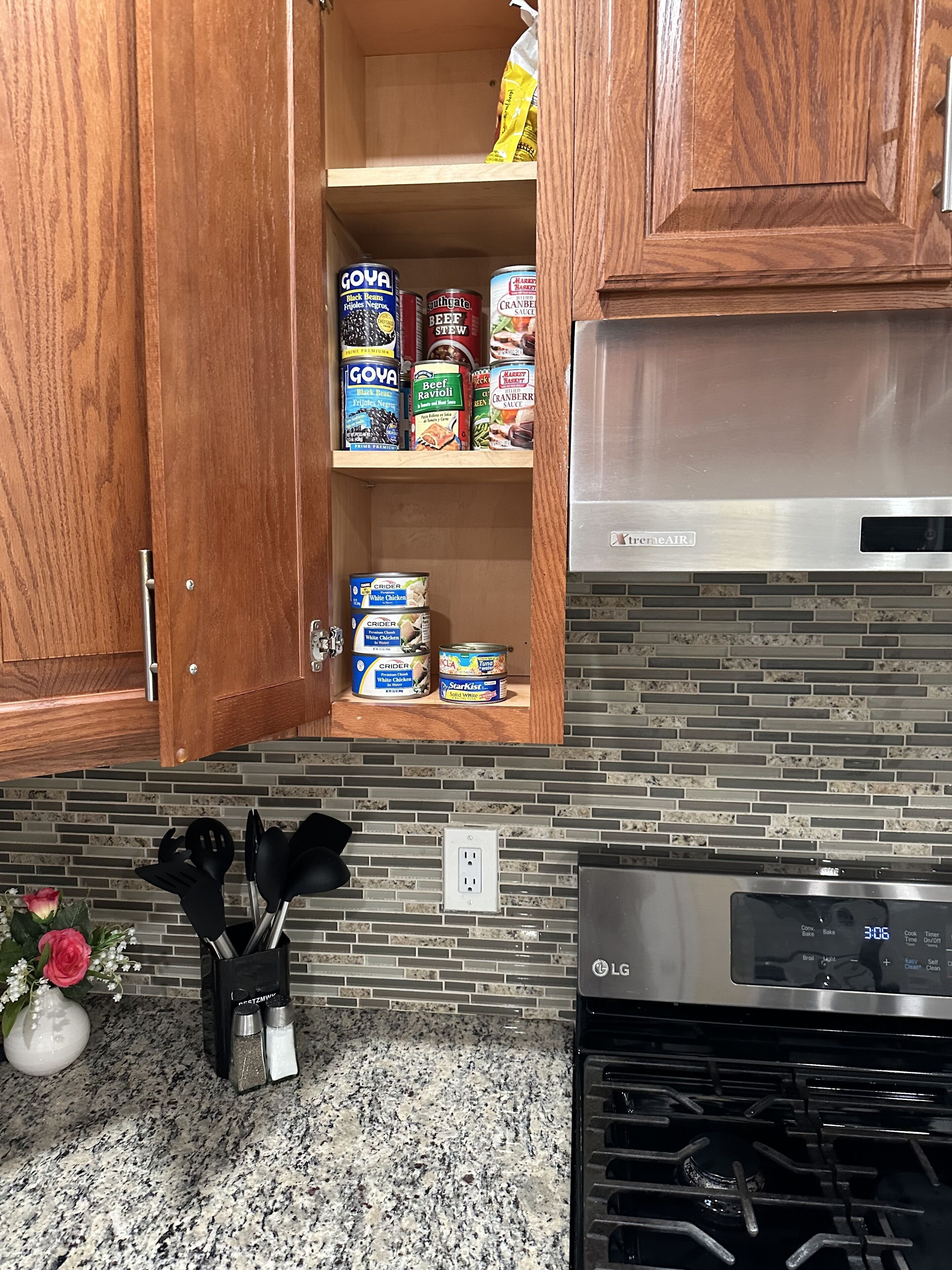 A kitchen with wooden cabinets, a stainless steel range hood, and a granite countertop.