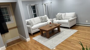 A living room with two white sofas, a wooden coffee table, and a patterned rug. - Charming quiet (Manchester)