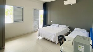 Ein Hotelzimmer mit zwei Betten, einem Schreibtisch mit Computer und einem Fenster mit Jalousien.