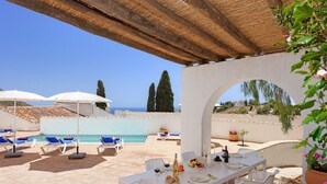 Eine Terrasse mit Esstisch, Lounge-Stühlen und Sonnenschirmen.