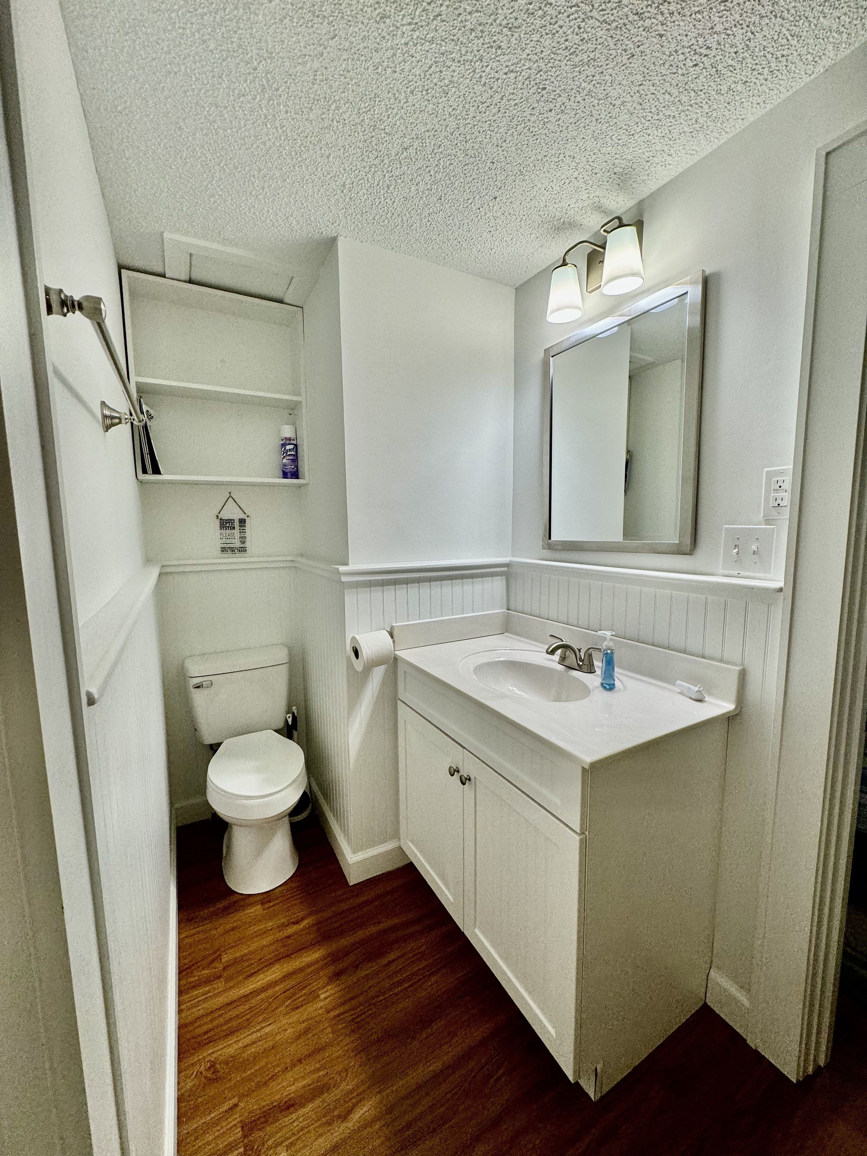 Ein Badezimmer mit Toilette, Waschbecken, Spiegel und Ablageflächen.