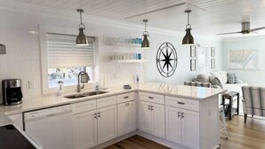 Una cocina moderna con armarios blancos, lavavajillas integrado e iluminación colgante.