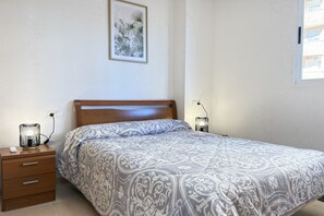Un dormitorio con cama, mesita de noche, lámpara y decoración en la pared.