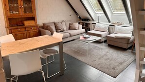 Un espace de vie de style loft comprenant un coin repas, un ensemble de canapés et un coin cuisine avec un meuble en bois.