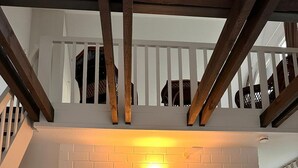 Un intérieur moderne avec un escalier, des murs en briques blanches et un coin repas comprenant des chaises et une table, le tout dans des tons blancs.