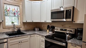 Una cucina moderna con mobili bianchi, elettrodomestici in acciaio inossidabile e soffitto in legno.