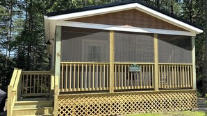 A wooden cabin with a covered porch and a sign reading "Kimball Cottage."