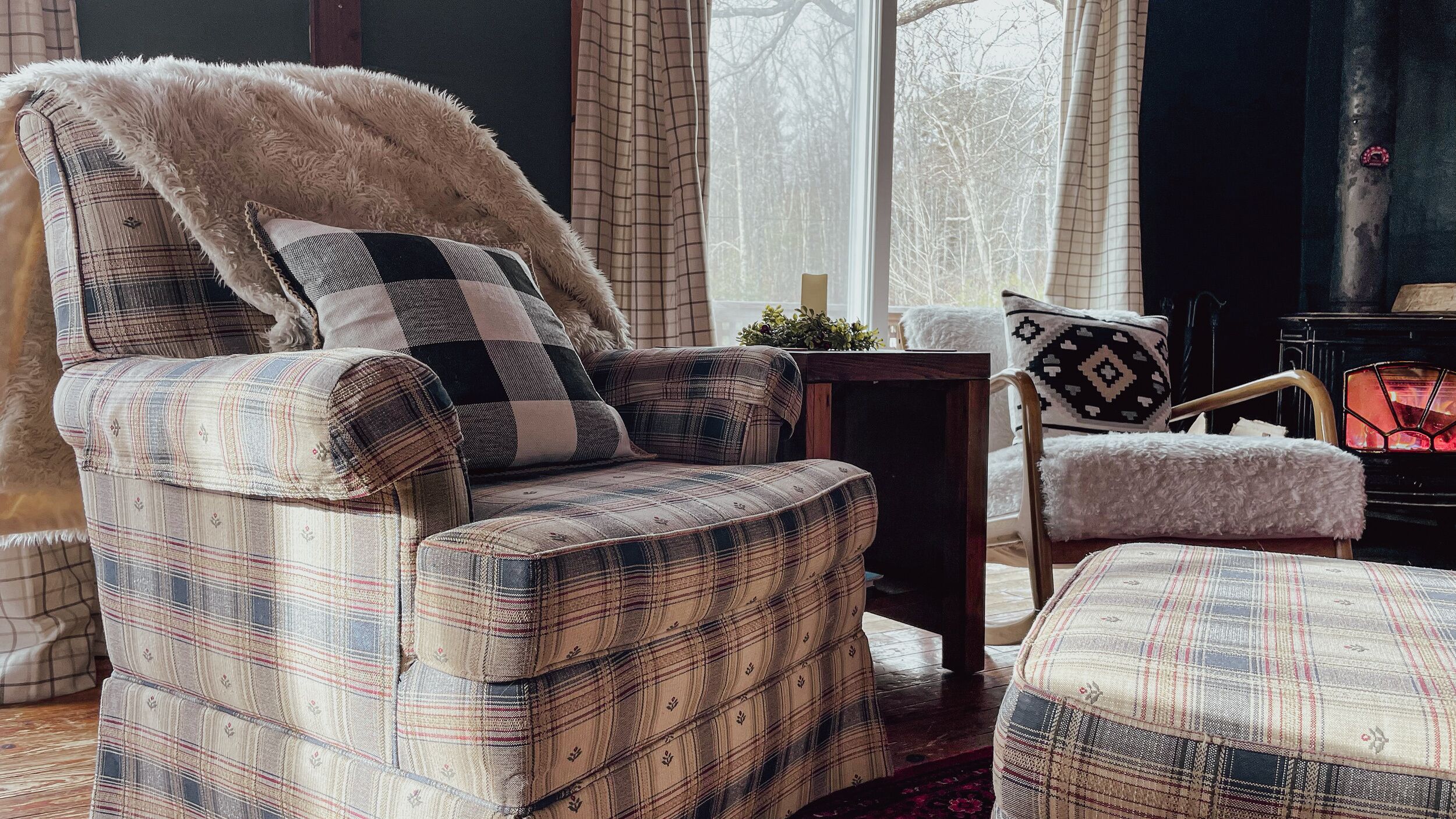 A cozy living room with a plaid-patterned armchair, a matching ottoman, and a small side table with a plant.