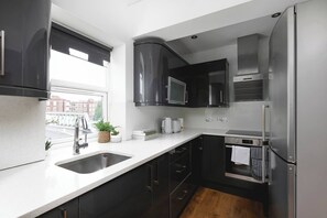Una cocina moderna con un refrigerador de acero inoxidable, un microondas y un horno empotrado.
