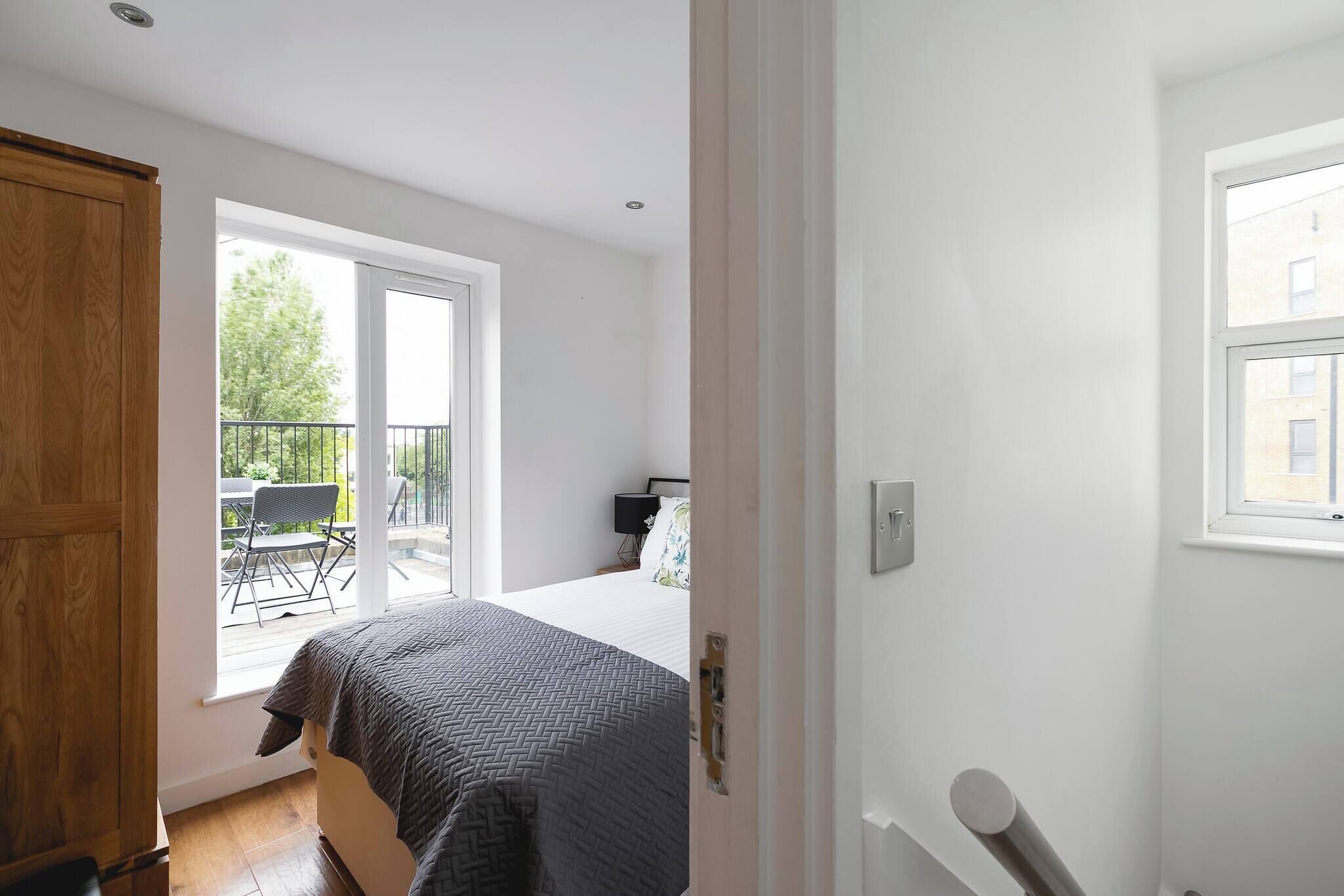 A bedroom with a bed, a window, and a balcony.