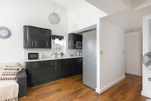 A modern kitchen with black cabinets, a microwave, and a fan. - Skyvillion - Central Ldn 3bed Flat Ladbroke Grove (London)