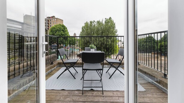 A balcony with a table and chairs, a potted plant, and a view of buildings and trees. - Skyvillion - Central Ldn 3bed Flat Ladbroke Grove (London)