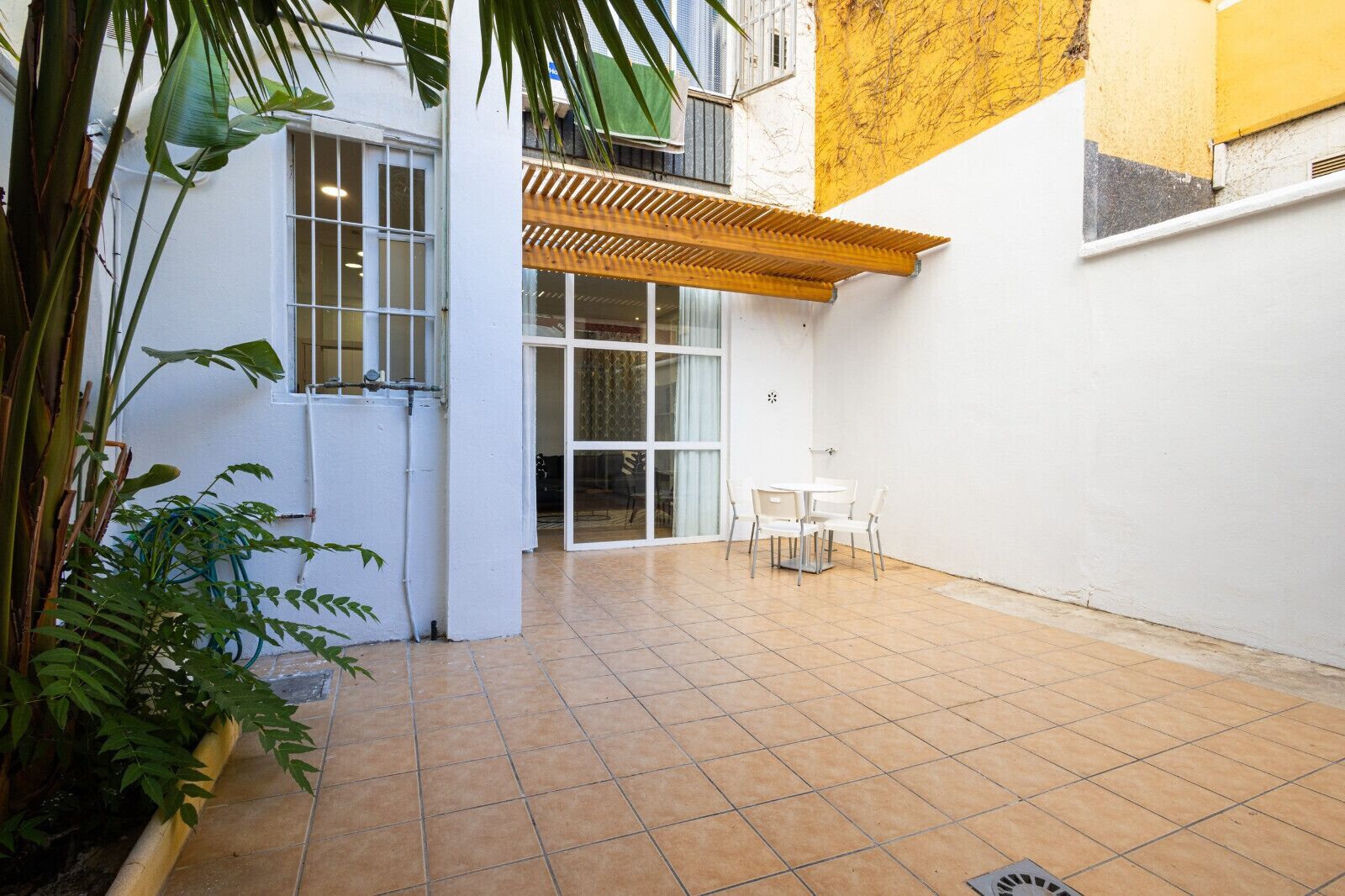 Eine Terrasse mit Fliesenboden, einer Holzhütte und einer weißen Wand.
