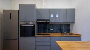 A compact kitchen with a built-in oven, a stainless steel refrigerator, and a wooden countertop. - The Vella Apartment by Florit Flats (Valencia)