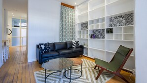 A modern living room with a sofa, a glass coffee table, a patterned rug, and a bookshelf. - The Vella Apartment by Florit Flats (Valencia)
