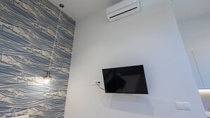 Un baño moderno con televisor montado en la pared, equipo de aire acondicionado y papel tapiz estampado.