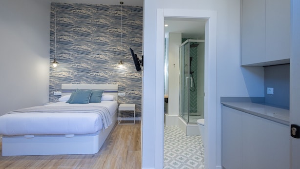 Un dormitorio moderno con una cama, mesita de noche y pared con estampado.