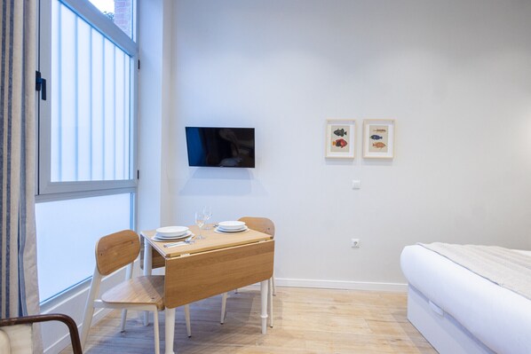 A modern room with a wooden dining table set for two, a bed, and a TV mounted on the wall. - The Mediterraneo Apartment 02 by Florit Flats (Valencia)