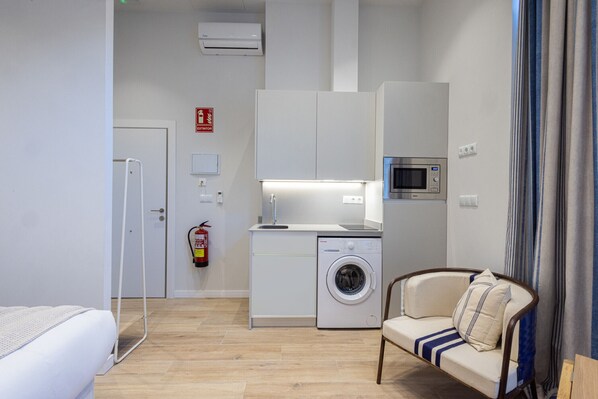 A compact hotel room with a bed, a washing machine, a microwave, and a sofa. - The Mediterraneo Apartment 02 by Florit Flats (Valencia)