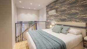 Une chambre à coucher comprenant un lit, une tête de lit, une table de chevet et un climatiseur fixé au mur.