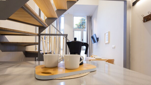 Une cuisine moderne avec une table basse en bois, deux tasses blanches et une machine à café.
