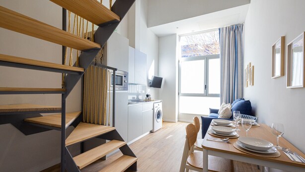 Una cocina moderna con microondas integrado, lavadora y comedor con mesa lista para cuatro.
