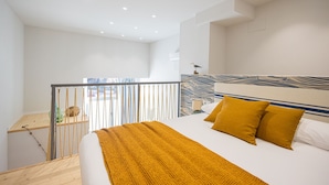 A modern hotel room with a large bed, a balcony with a view, and a distinctive headboard design.