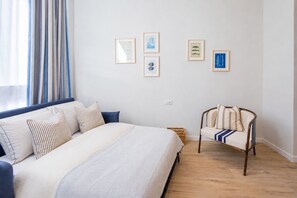 A bedroom with a bed, a chair, and four framed pictures on the wall.