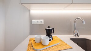 Eine moderne Küche mit integrierter Kaffeemaschine, zwei weiße Tassen auf einem Holztablett und einem Edelstahl-Spülbecken.