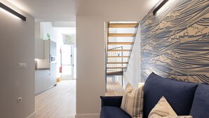 Ein modernes Wohnzimmer mit einem blauen Sofa, einer Holztreppe und einer Wand mit Muster.
