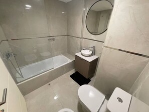 A modern bathroom with a glass-enclosed bathtub, a sink, and a toilet. - Modern & Cozy Studio in San Telmo With Exclusive Service no 1 (Buenos Aires)