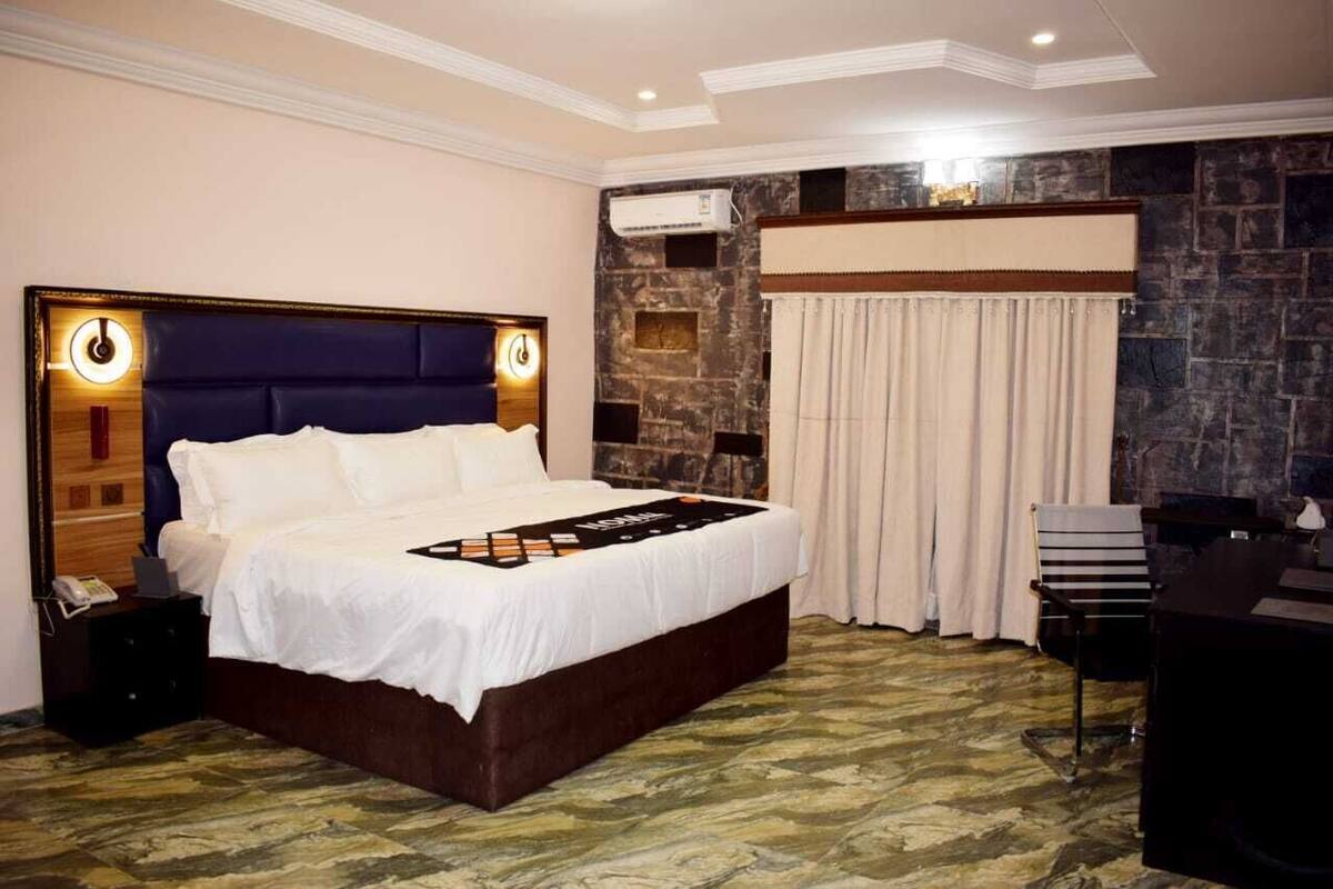 A hotel room with a large bed, a desk, and a stone accent wall.