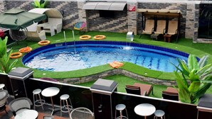 A swimming pool with artificial grass, surrounded by outdoor seating and a barbecue area. - Place Tochil (Owerri)