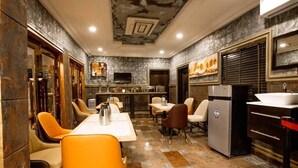 A restaurant with a long counter, orange chairs, a refrigerator, and a sink. - Place Tochil (Owerri)