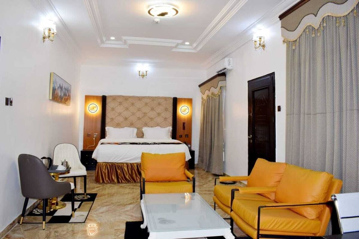 A hotel room with a large bed, a desk, a sofa, and a coffee table.