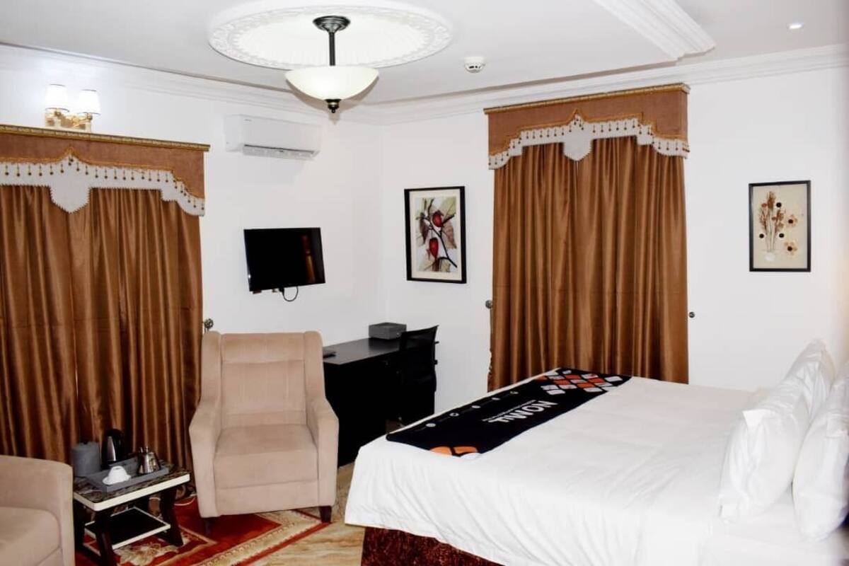 A hotel room with a bed, a desk, a chair, and a television.