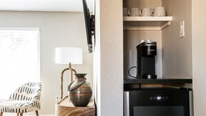 A compact kitchen with a built-in coffee maker, a refrigerator, and a shelf with cups. - Bab Al Shams | Pet-friendly | Great Backyard (Fredericksburg)