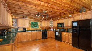 Una cocina amplia con armarios de madera, un refrigerador negro y techo de madera.