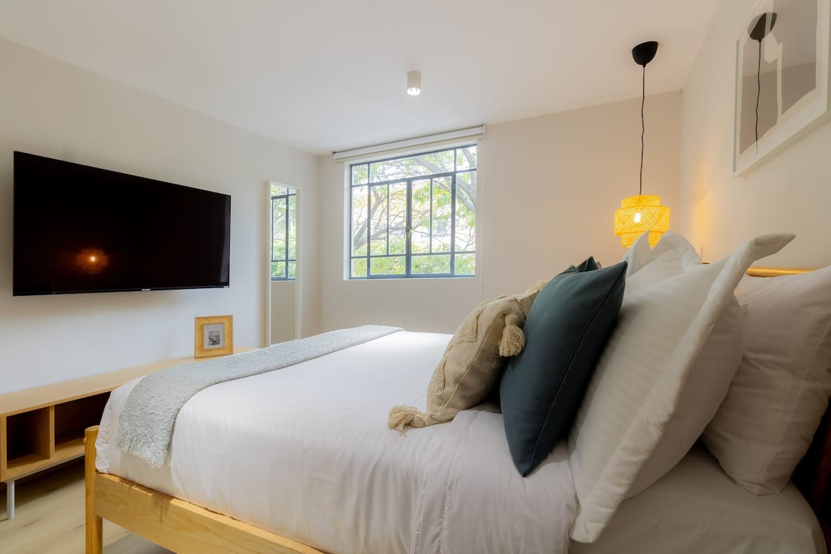 Una camera da letto con un letto, una televisione, una finestra e una lampada da comodino.