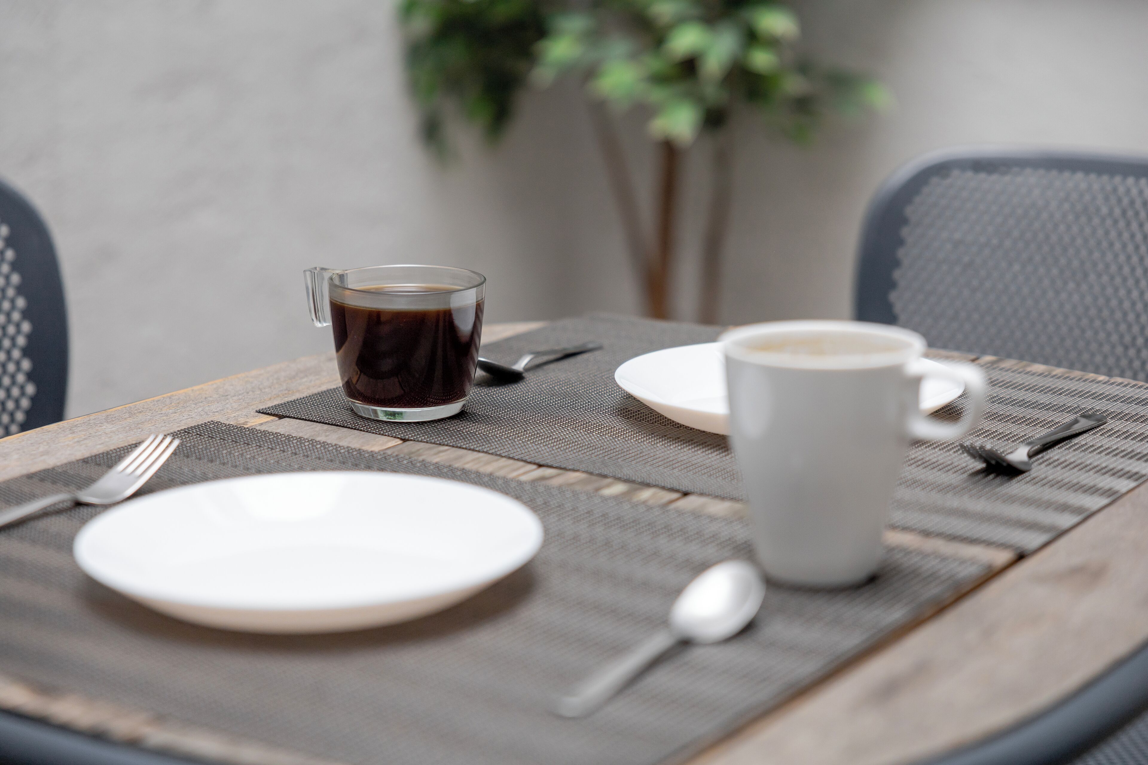 Ein Tisch, gedeckt mit einer Kaffeetasse, einem Teller und Besteck.