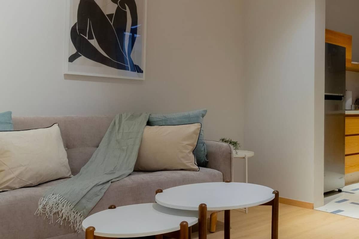 Un soggiorno con un divano, due tavolini e un quadro astratto appeso al muro.