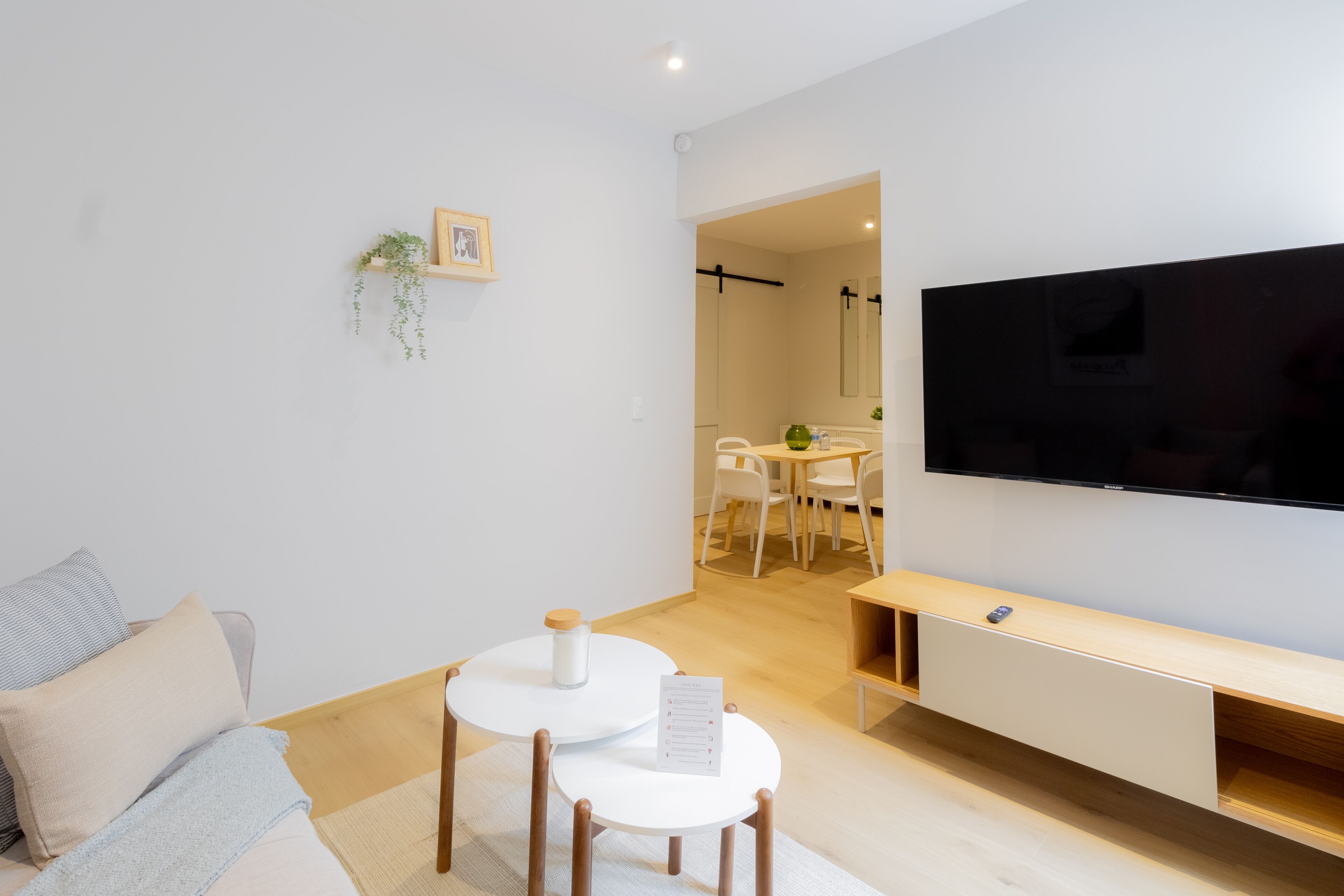 A modern living room with a sofa, two small tables, a TV, and a wooden bench.