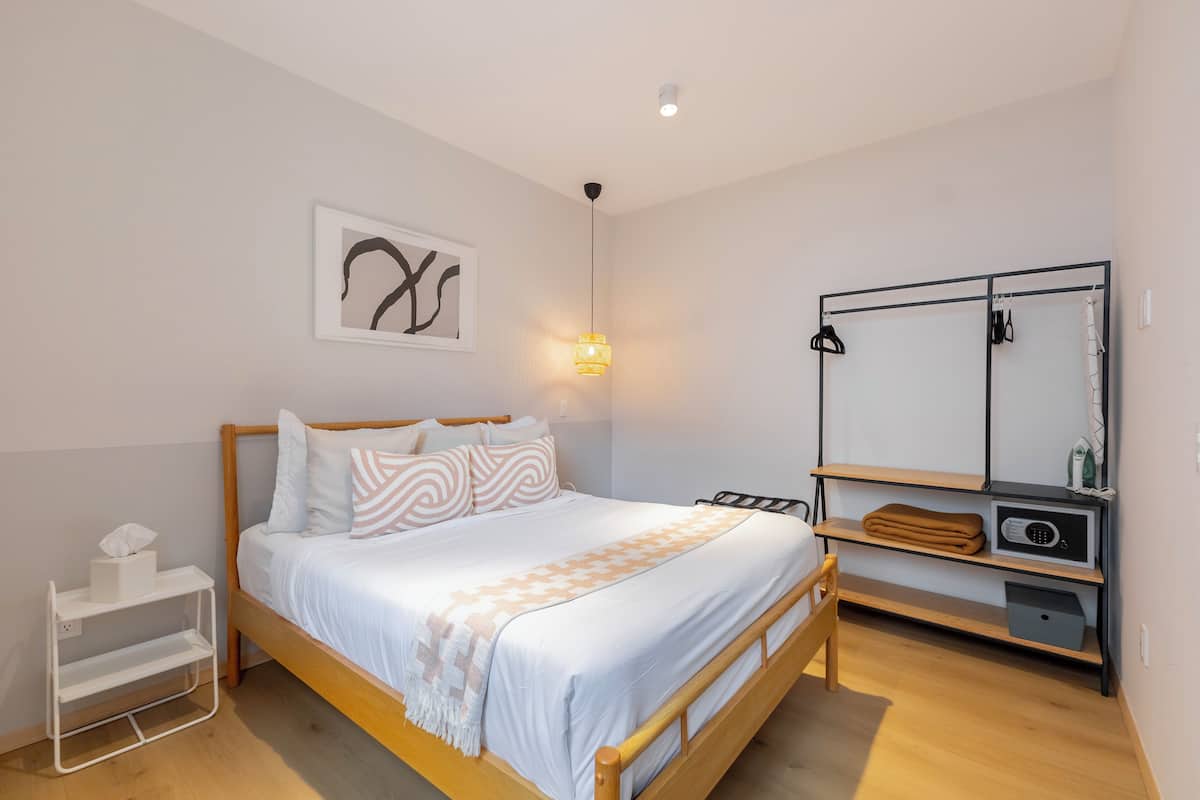 Una camera da letto ordinata con un letto, comodini, un armadio e una mensola a parete.