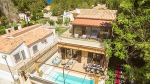 Ein zweistöckiges Haus mit Swimmingpool, einer überdachten Terrasse und Blick auf die umliegende Landschaft.