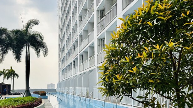 Un hôtel moderne doté d’une piscine, entouré d’une végétation luxuriante et de palmiers.