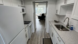 A modern kitchen with white cabinetry, a built-in microwave, and a granite countertop. - 2 Bedroom Longboat Key Beachside Paradise. Steps from the Beach! (Longboat Key)