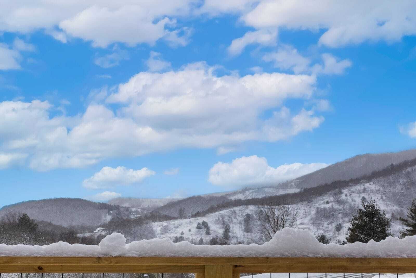 A snowy mountain landscape with a wooden fence in the foreground.