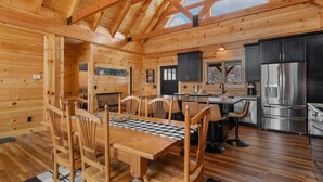 A log cabin interior with a dining area, kitchen, and a large skylight. - Custom-Built Log Cabin with Long Range Views (Banner Elk)
