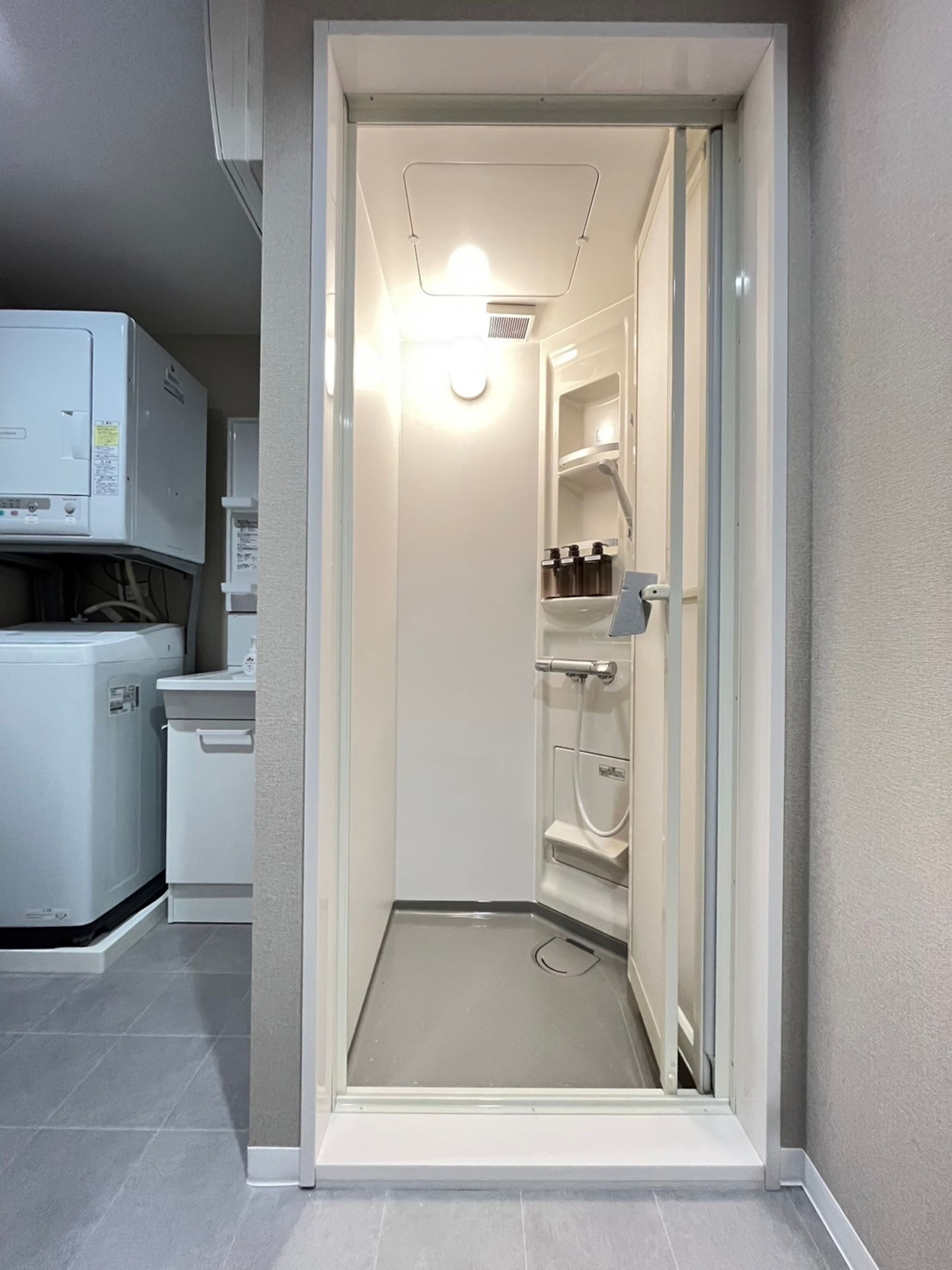 A compact, modern bathroom with a built-in shower, a toilet, and a sink.